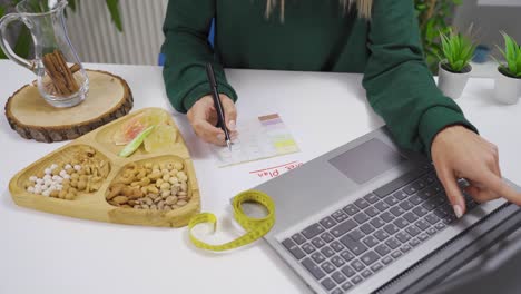 la mujer está preparando una lista de dieta mirando en internet en casa.