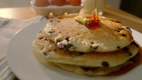 syrup is poured onto a stack of pancakes