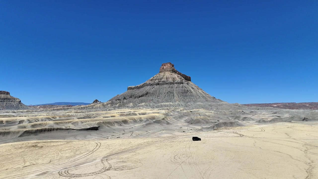 Veduta aerea statica di un veicolo che attraversa il deserto oltre Factory Butte, Utah.