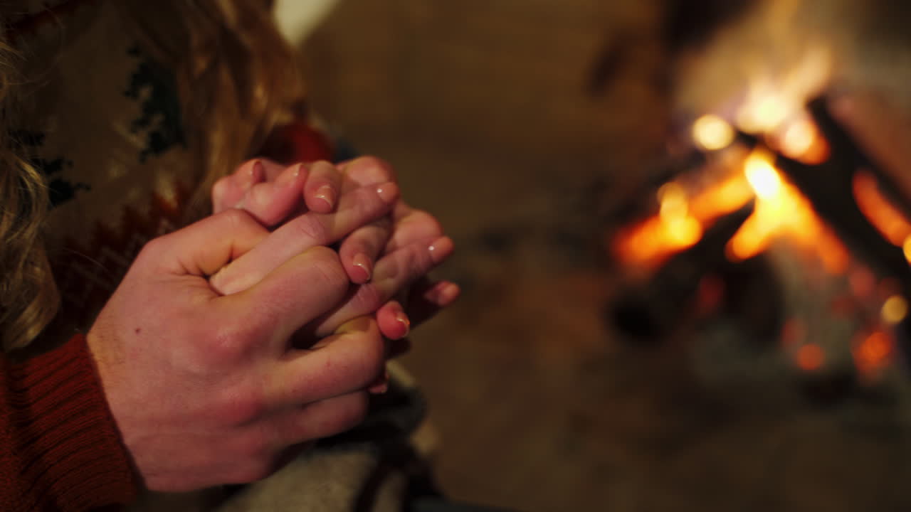 Close up of couple hands touching each other at bonfire light. Lovers petting during their date. Love and relationship.