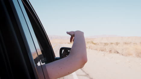 Beifahrerin-Mit-Arm-Aus-Dem-Autofenster-Auf-Wüstenfahrt