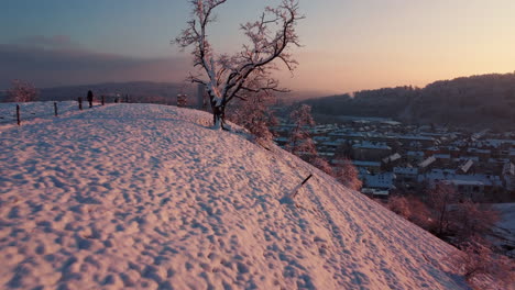 flying over the edge of a snowy hill during a red winter sunset