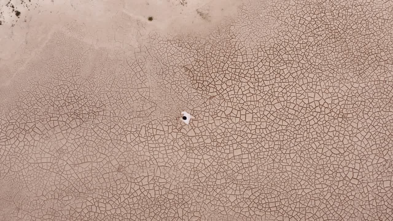 가뭄 시즌 동안 건조한 사막 땅을 걷는 외로운 남자 - 공중 하향식