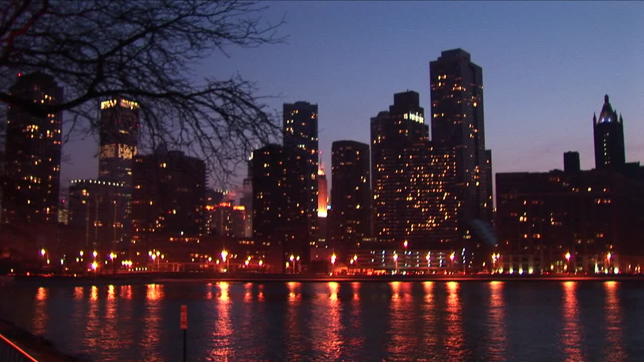 la cámara se acerca a la parte superior de una torre de rascacielos iluminada desde una vista de gran angular del horizonte de chicago