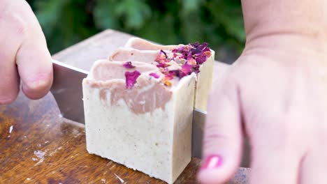 a women gently slices a newly made block of handmade soap with a sharp knife