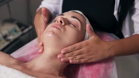 closeup view of a professional cosmetologist's hands making face and neck massage in spa salon