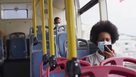 hombre y mujer afroamericanos con máscaras faciales sentados en el autobús