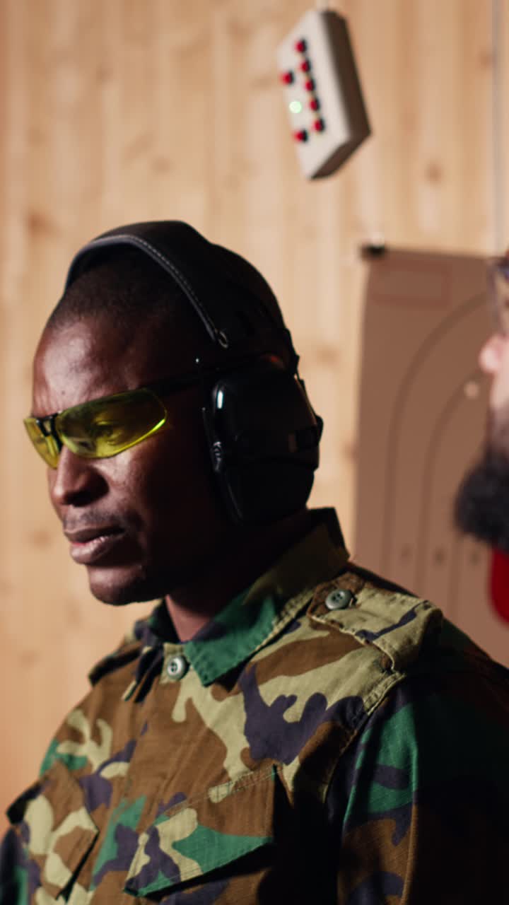 Vertical video Portrait of happy army soldiers in shooting gallery comparing targets shot