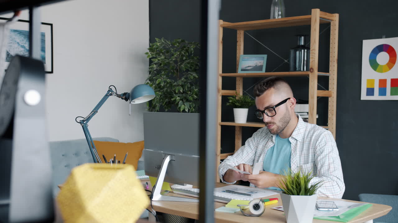 Uomo che lavora in un ufficio domestico, esaminando campioni di colore