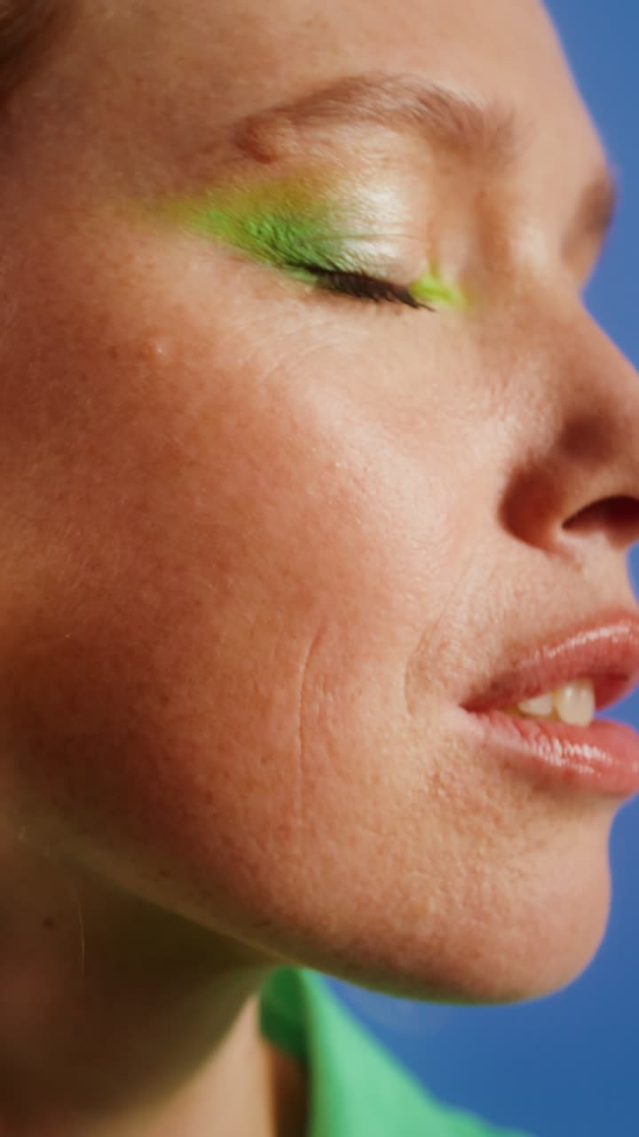 Close-up of a woman with green eyeshadow and makeup brush