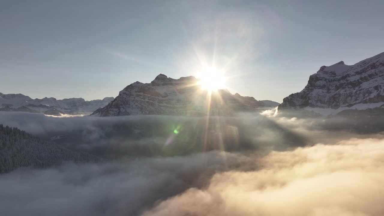 Sun rising behind Rautispitz in the Glärnisch mountain range, part of the Swiss Alps, creating a stunning natural scene.