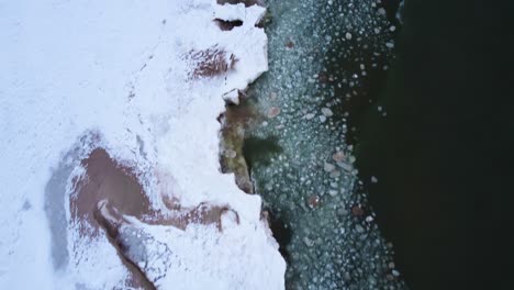 4k drone of waves crashing into frozen shoreline