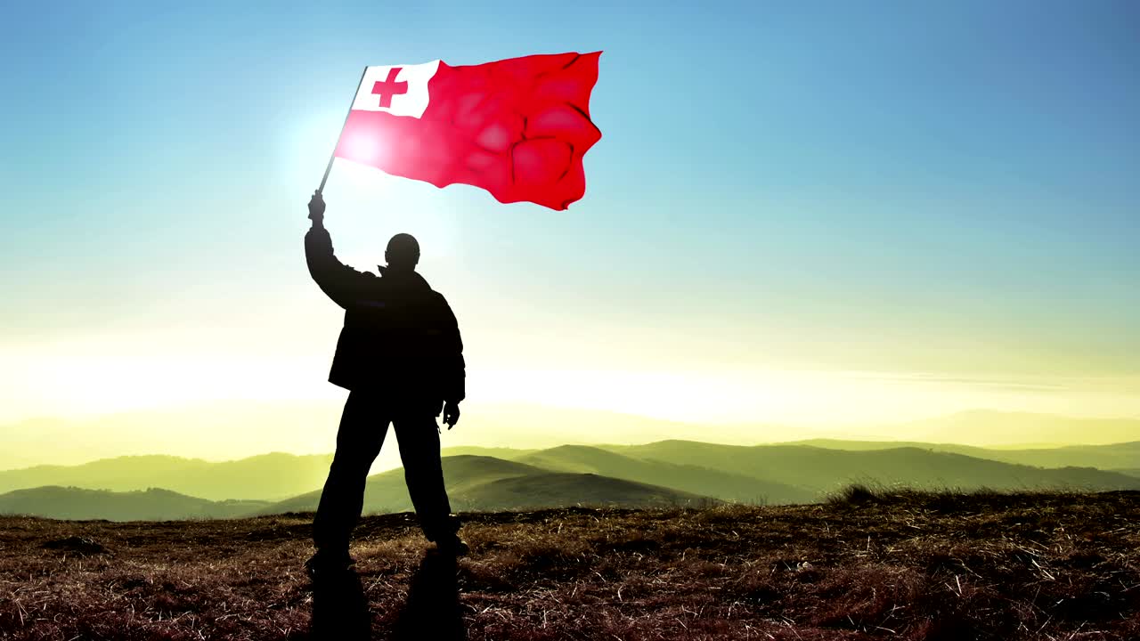 exitoso hombre silueta ganador agitando bandera de tonga en la parte superior del pico de la montaña, fondo de bucle cinemagraph