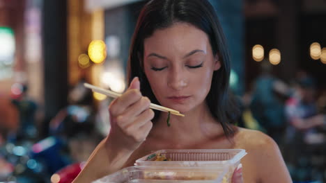 woman eating noodles at night market