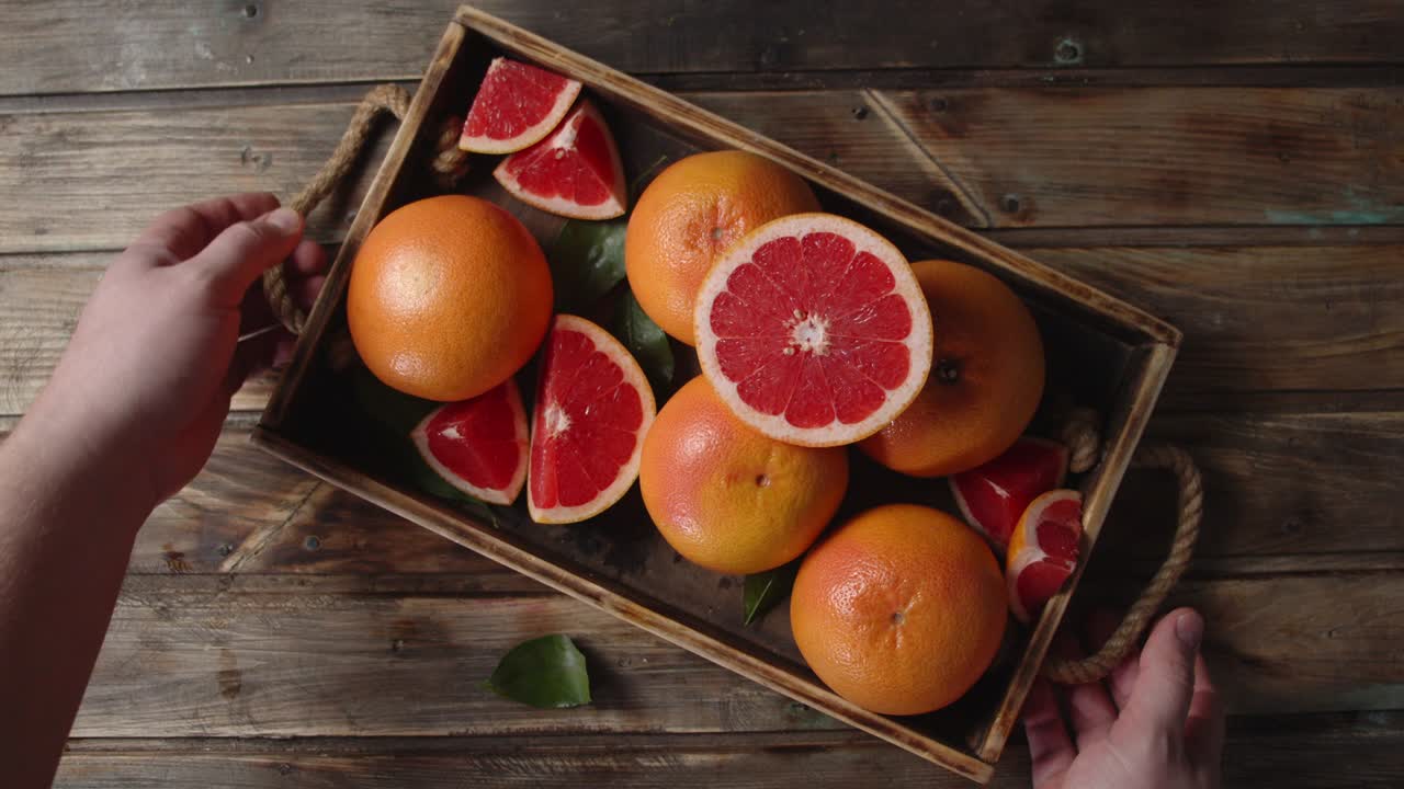 The hands of the man takes the tray with fresh grapefruit.