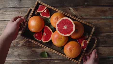 the hands of the man takes the tray with fresh grapefruit.