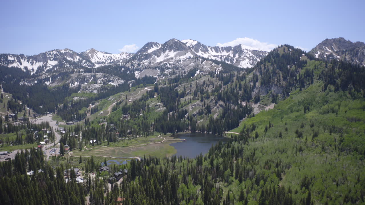 Volo di drone aereo sopra il Guardsman Pass vicino a Park City, Utah, in estate. La tortuosa strada di montagna, le foreste lussureggianti e le vette aspre sotto cieli sereni catturano la bellezza della catena montuosa Wasatch