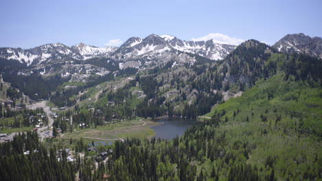 aerial drone flight over guardsman pass near park city, utah in summer. winding mountain road, lush forests, and rugged peaks under clear skies capture the beauty of the wasatch range