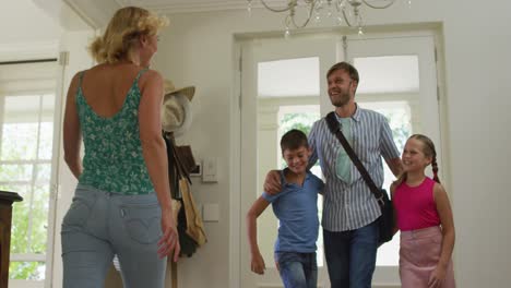 Caucasian-mother-son-and-daughter-embracing-and-welcoming-father-coming-home