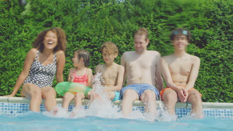 Retrato-De-Una-Familia-Multirracial-Relajándose-En-La-Piscina-Durante-Las-Vacaciones-De-Verano-Tomada-Desde-El-Agua