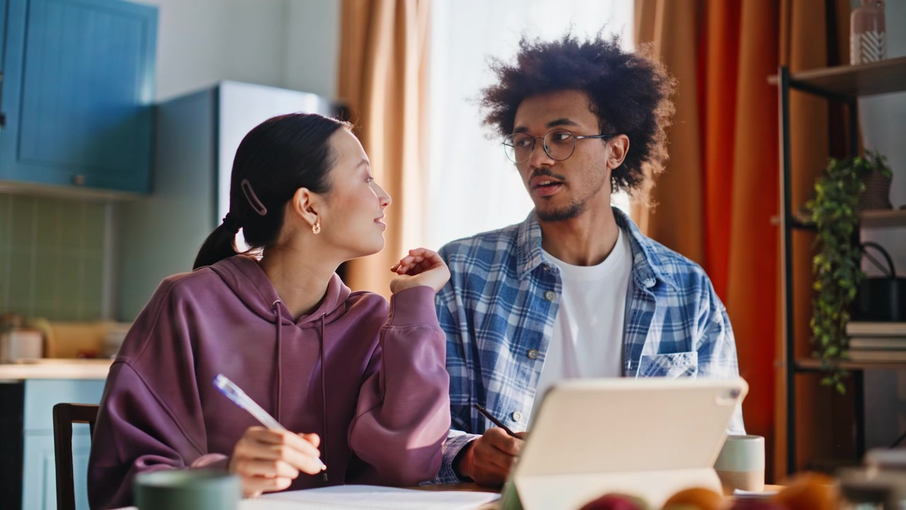 Multiethnic couple studying together home kitchen. Closeup pair doing homework.