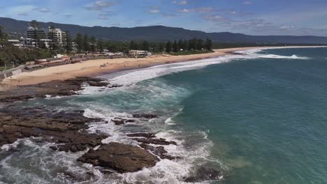 Sobre-Rocas-Y-Surfear-Hacia-Las-Instalaciones-De-Salvamento-De-Surf-En-La-Playa-De-North-Wollongong-Con-Edificios-Al-Fondo