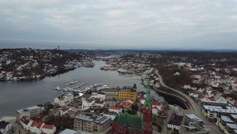 arendal norway - flying above city center with trinity church and tyvholmen while looking west towards stromsbu and bie - cloudy morning aerial