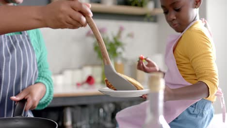 Happy-african-american-mother-and-daughter-preparing-pancakes-in-kitchen,-slow-motion