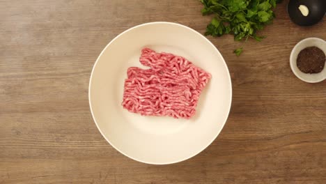 Crop-cook-putting-minced-meat-in-bowl-plate