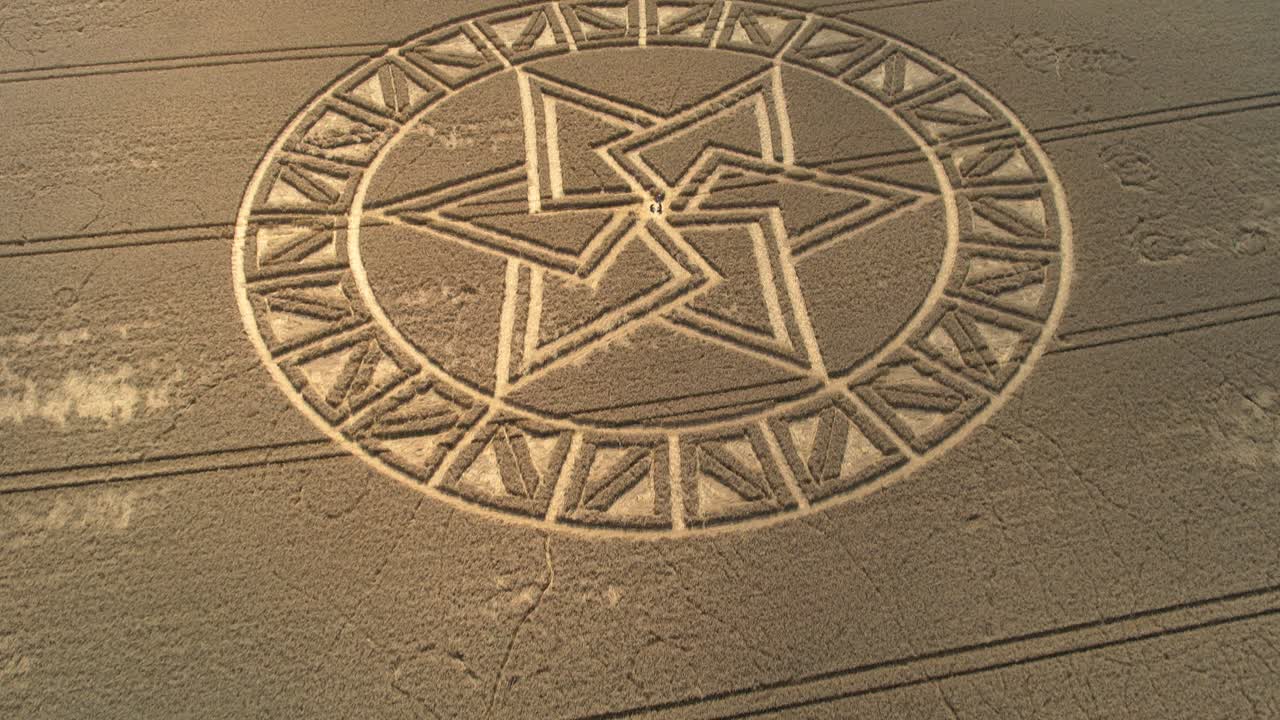 Overlapping West Meon mysterious crop circle pattern aerial view push in tilt down above golden farmland