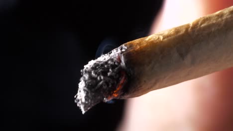 primer plano de un cigarrillo enrollado encendido con llama ardiente inhalada - fumar búsqueda recreativa
