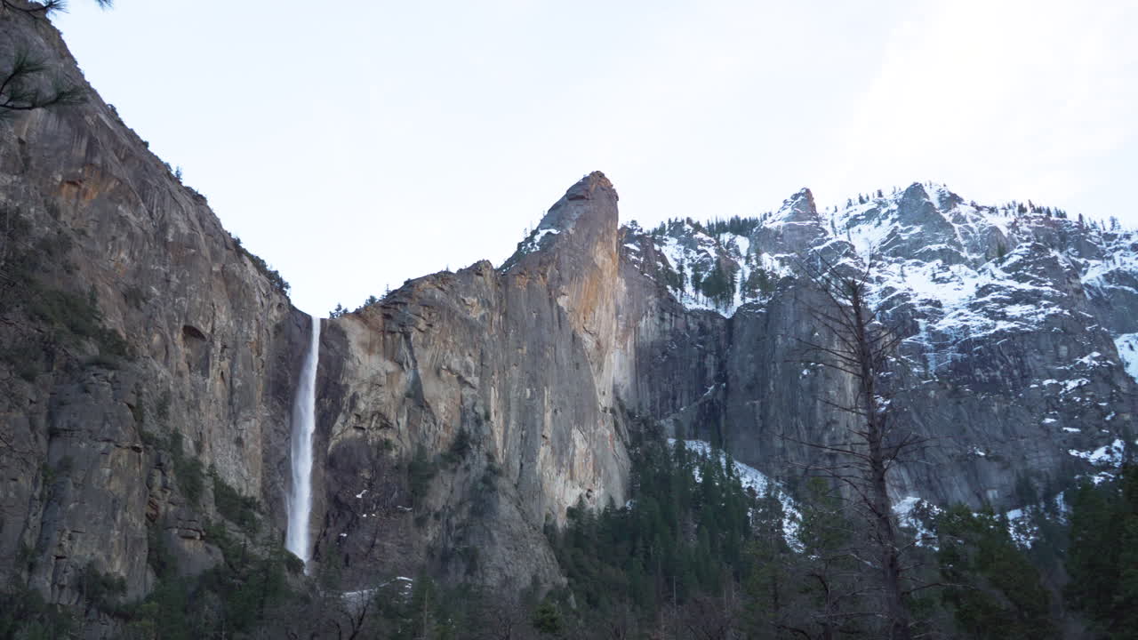 bridalveil cai no parque nacional de yosemite depois do pôr do sol cercado por picos cobertos de neve
