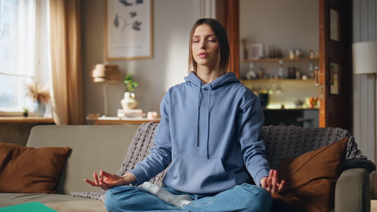 Woman meditating on couch at home