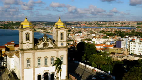 Vista-Aérea-De-La-Iglesia-De-Nosso-Senhor-Do-Bonfim,-La-Ciudad-Alrededor-Y-El-Océano-Al-Fondo,-El-Salvador,-Bahía,-Brasil