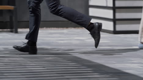 businessman legs running city street in black shoes closeup. morning commute