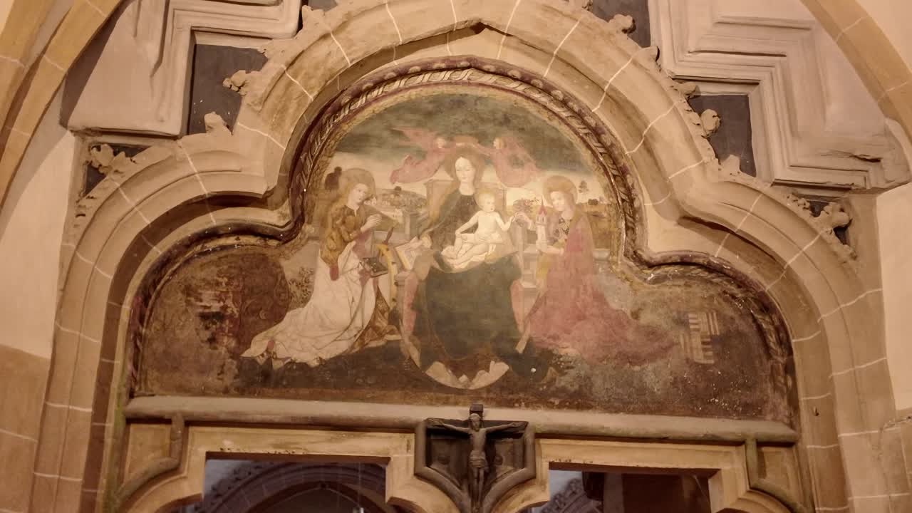 Primo piano di un affresco religioso all'interno della Chiesa Nera di Brașov, che rivela opere d'arte sacra storiche e dipinti murali dettagliati.