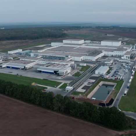 modern industrial zone outdoors. large factory with many buildings and cars moving on the road. manufacturing on beautiful nature background. aerial view.