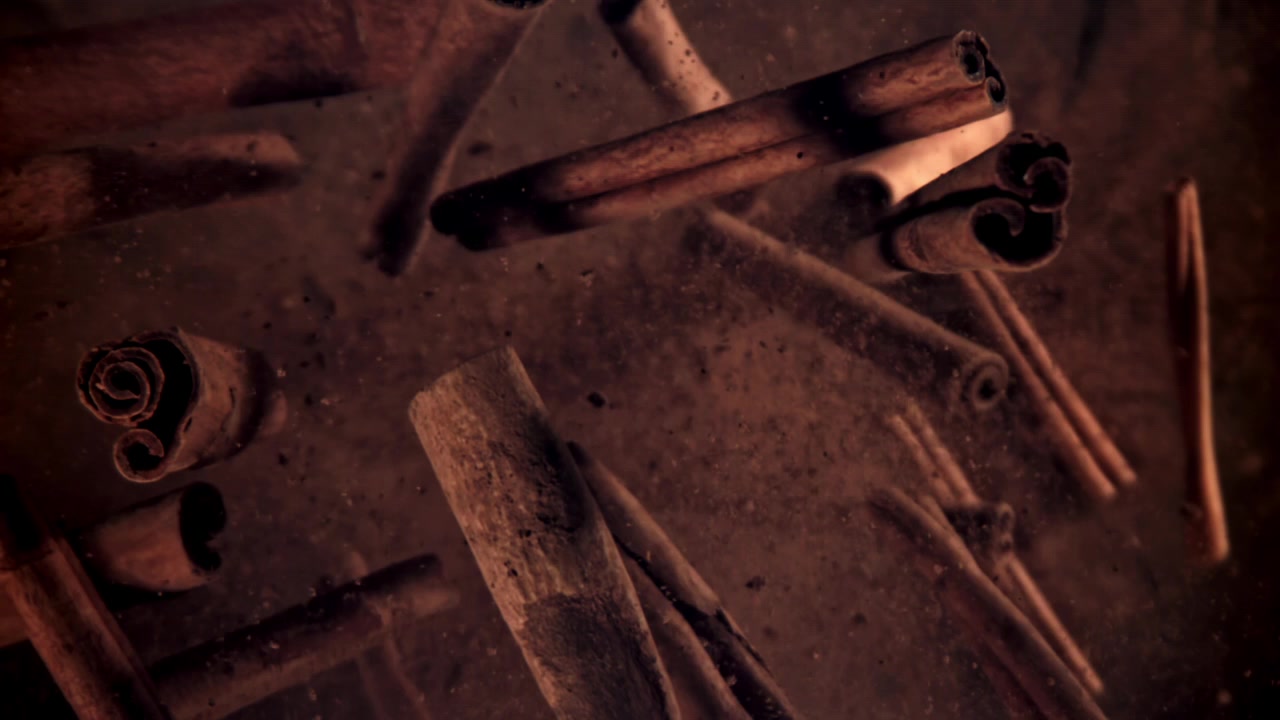 Slowmotion van kaneelpoeder dat op kaneelstokjes valt