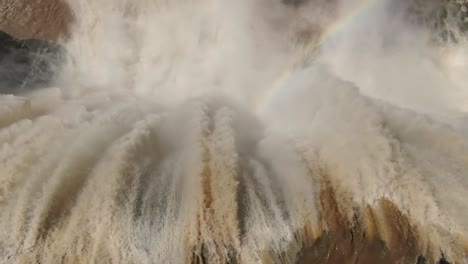 extreme close up top view of powerful raging water gushing over steep vertical cliff