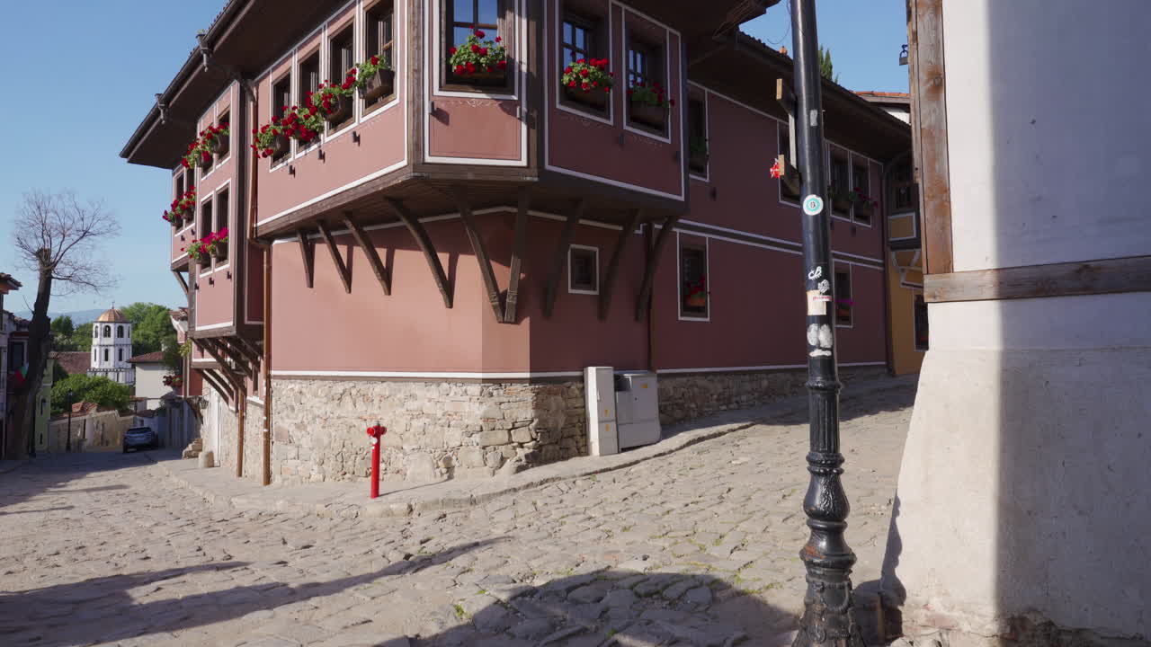 POV shot of a well-preserved Revival-era house in Plovdiv’s Old Town, adorned with red geraniums on its wooden windows