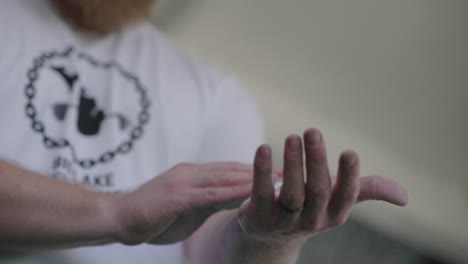 caucasian weight lifter putting on grip chalk before workout close up