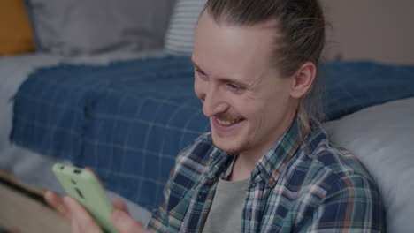 happy man using phone in bedroom