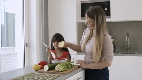 mom dressing salad with lemon in kitchen