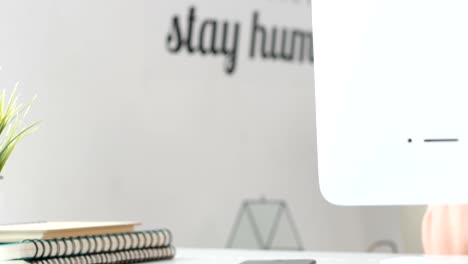 una mujer joven bebiendo café y trabajando en una computadora en la oficina de casa.