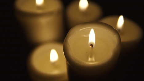 static shot of group four lighted candle, composition on black background, slow motion
