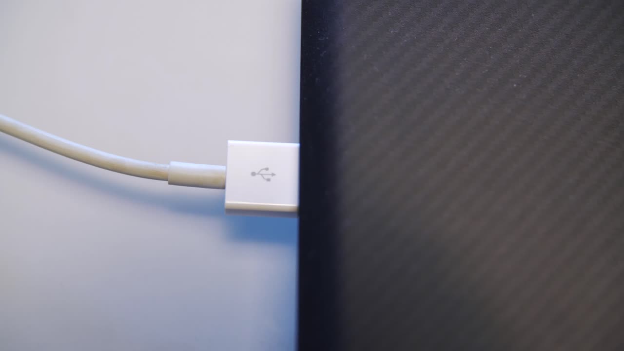 Hand connecting USB cable to a laptop