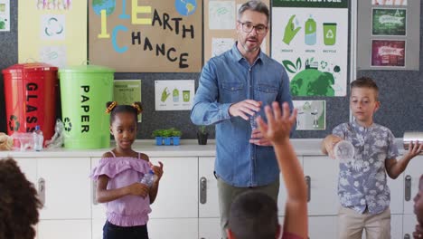diverse teacher and schoolchildren standing in classroom learning about recycling trash