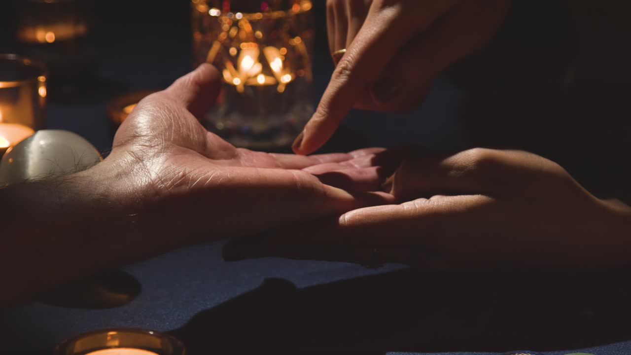 Close Up Of Woman Reading Man's Palm On Candlelit Table 1