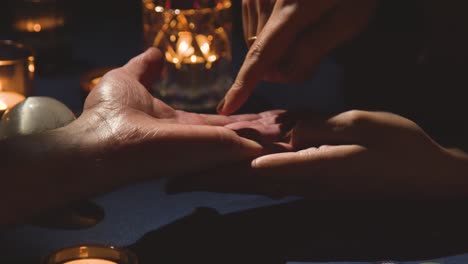 Close Up Of Woman Reading Man&#039;s Palm On Candlelit Table 1