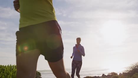 Pareja-Caucásica-Disfrutando-De-Tiempo-Libre-Junto-Al-Mar-En-Un-Sendero-Para-Correr-En-Un-Día-Soleado